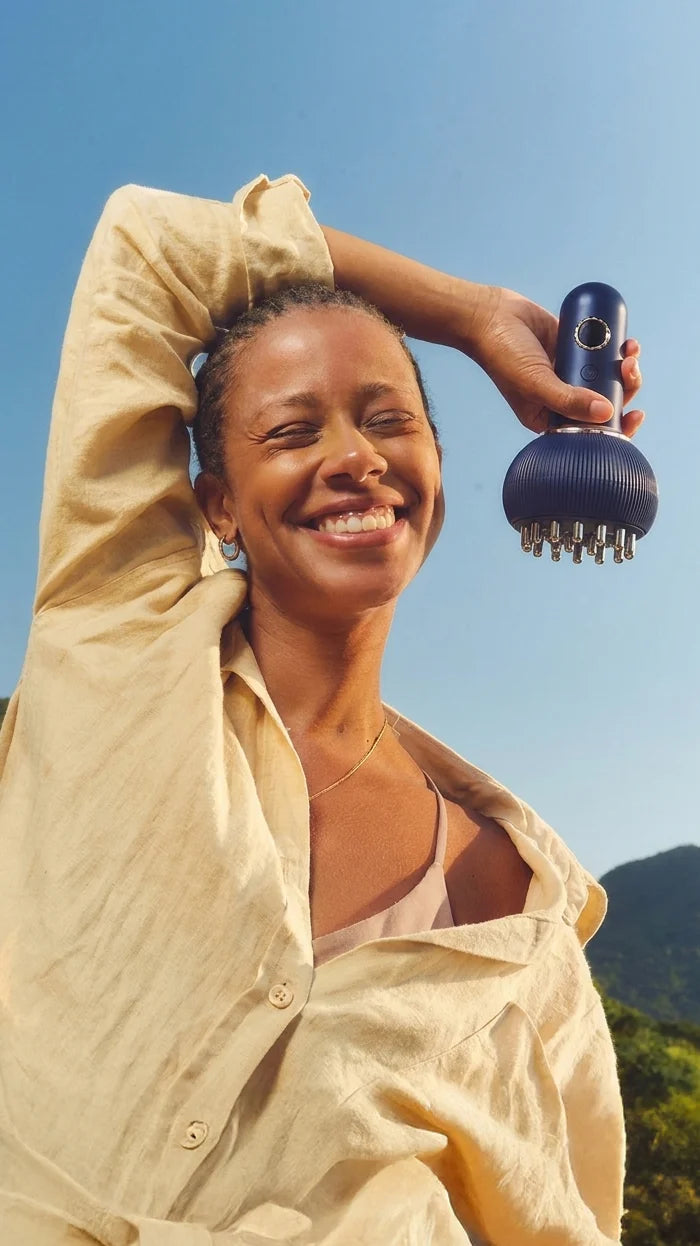 Smiling woman outdoors holding the ToneUp lymphatic massager, feeling lighter and less puffy